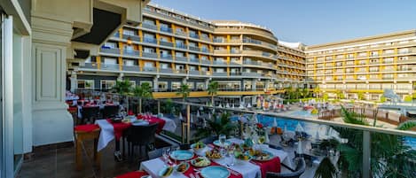 A hotel with multiple balconies, outdoor dining areas, and a swimming pool.