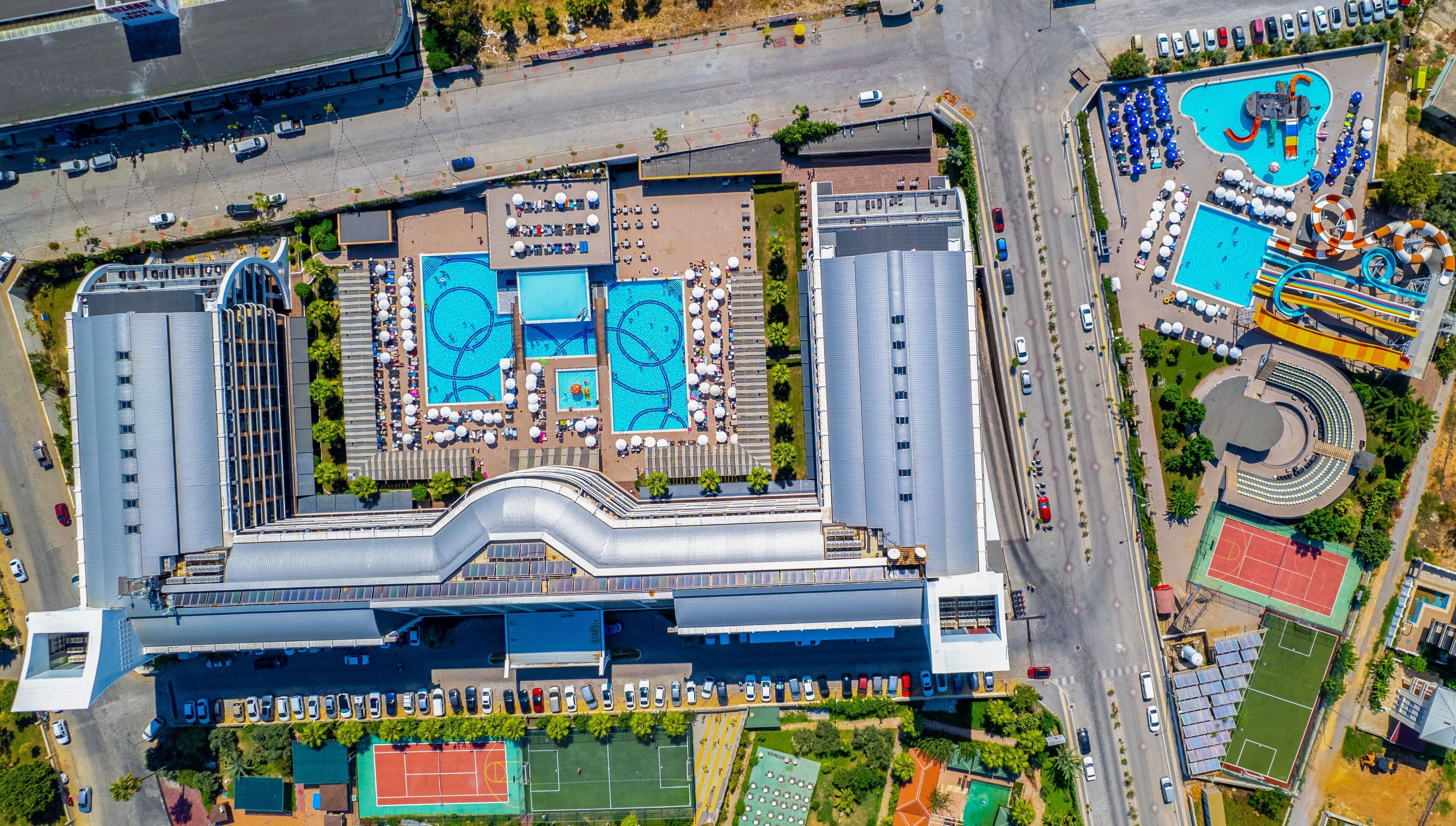 Un gran hotel con varias piscinas, cancha de tenis y parque acuático.