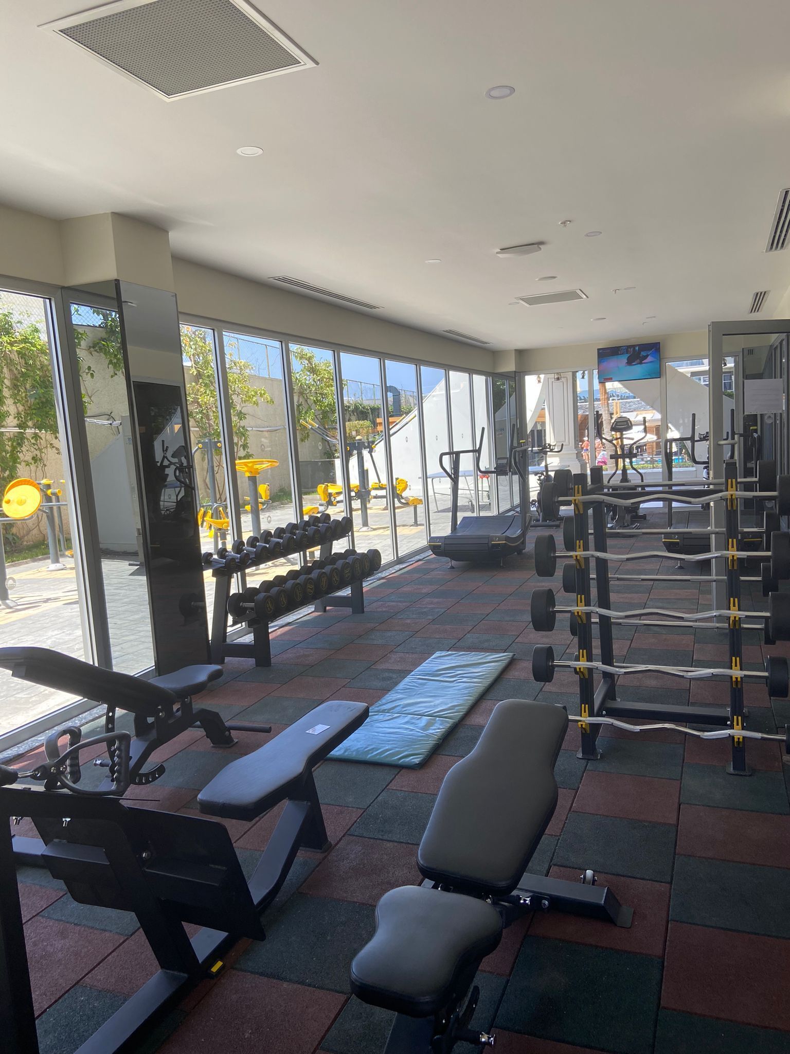 A gym with exercise equipment, benches, and a television screen.