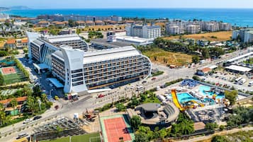 Un hotel moderno con fachada curva, varios pisos y zona de piscina en la azotea.