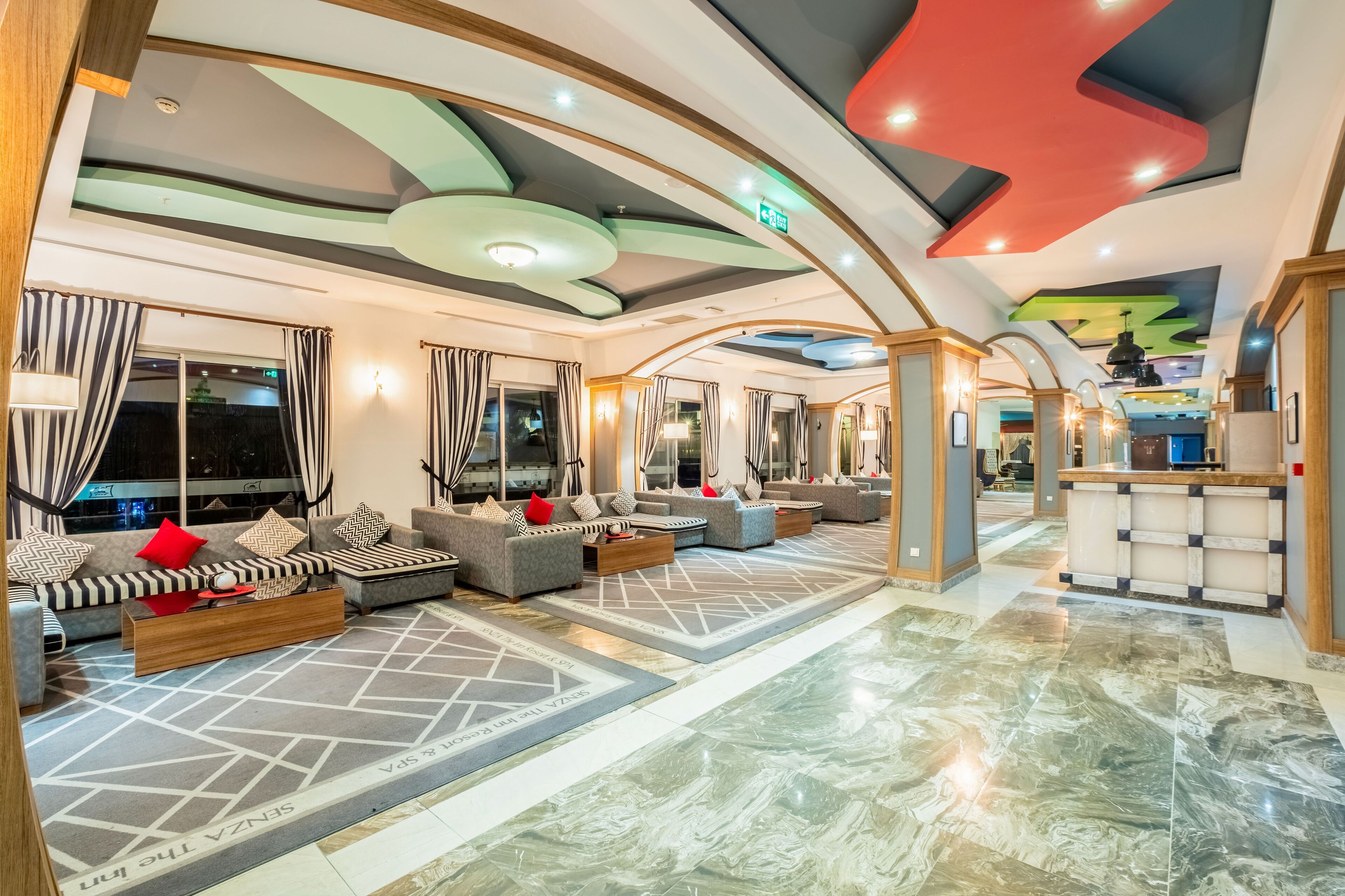 A spacious lobby with a modern design, featuring a seating area with sofas and a reception desk.