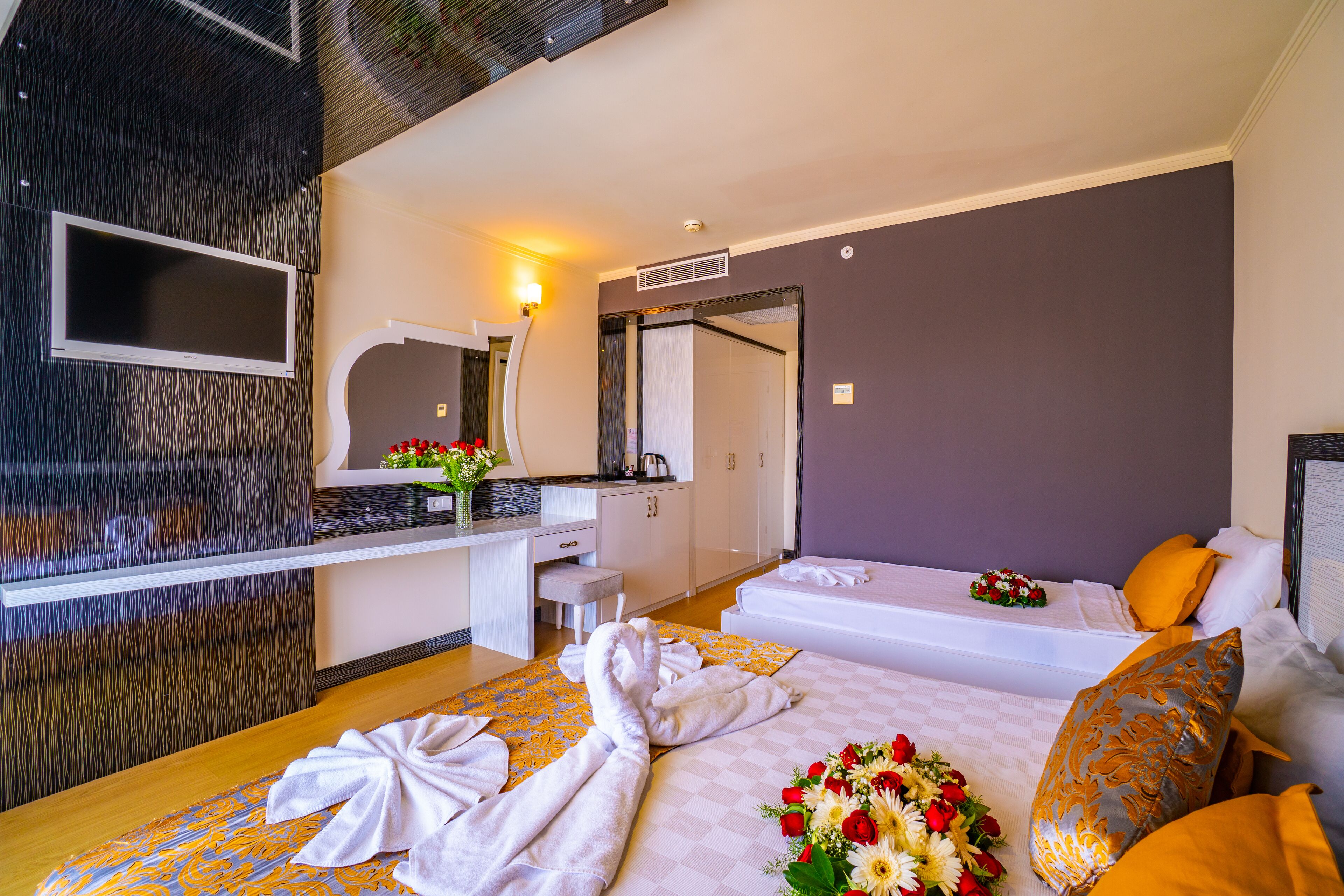 Quarto de hotel com duas camas, uma escrivaninha, televisão e banheiro.