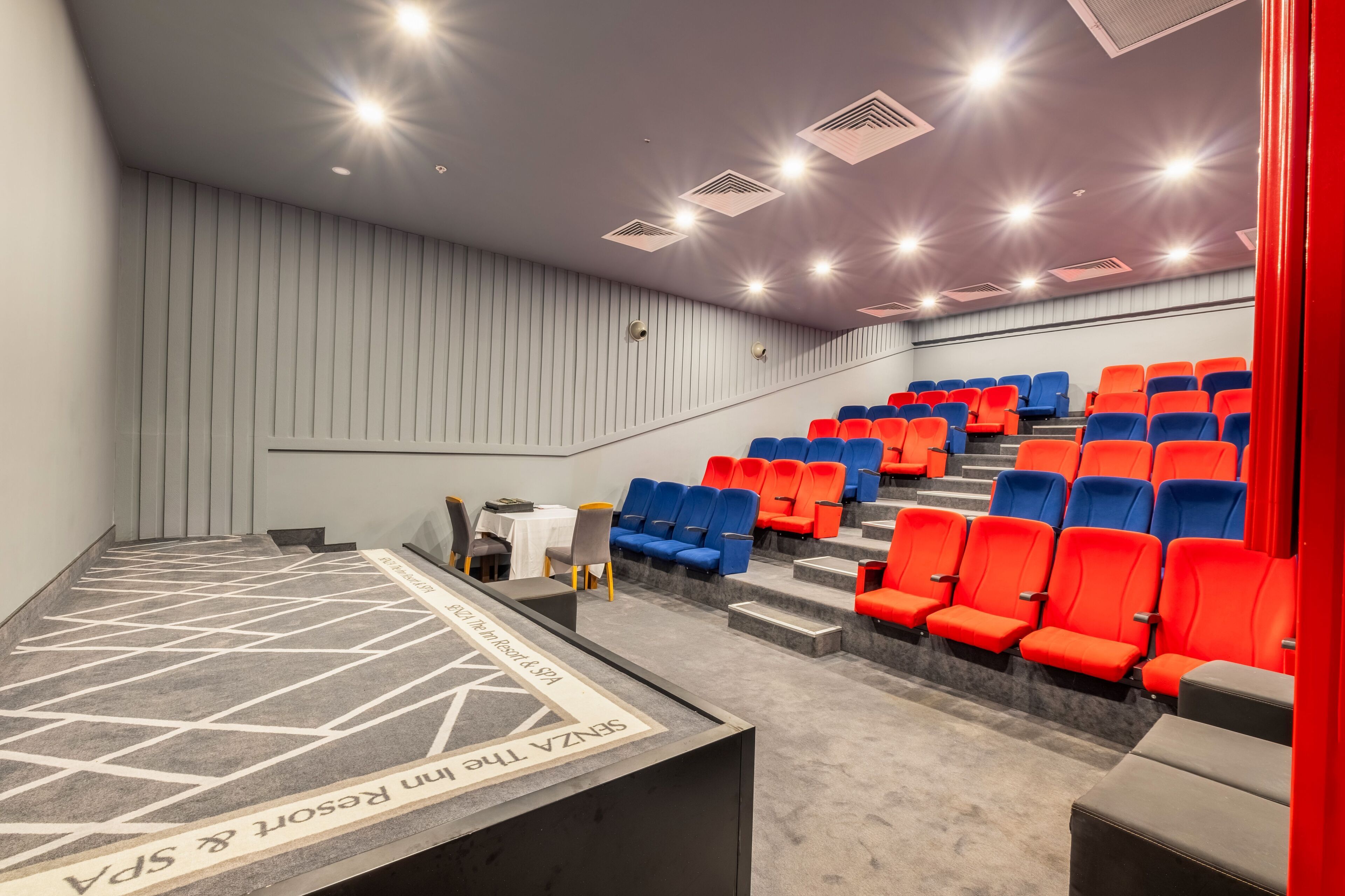 A theater with tiered seating, a stage, and a carpeted floor.