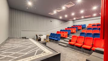A theater with tiered seating, a stage, and a carpeted floor.