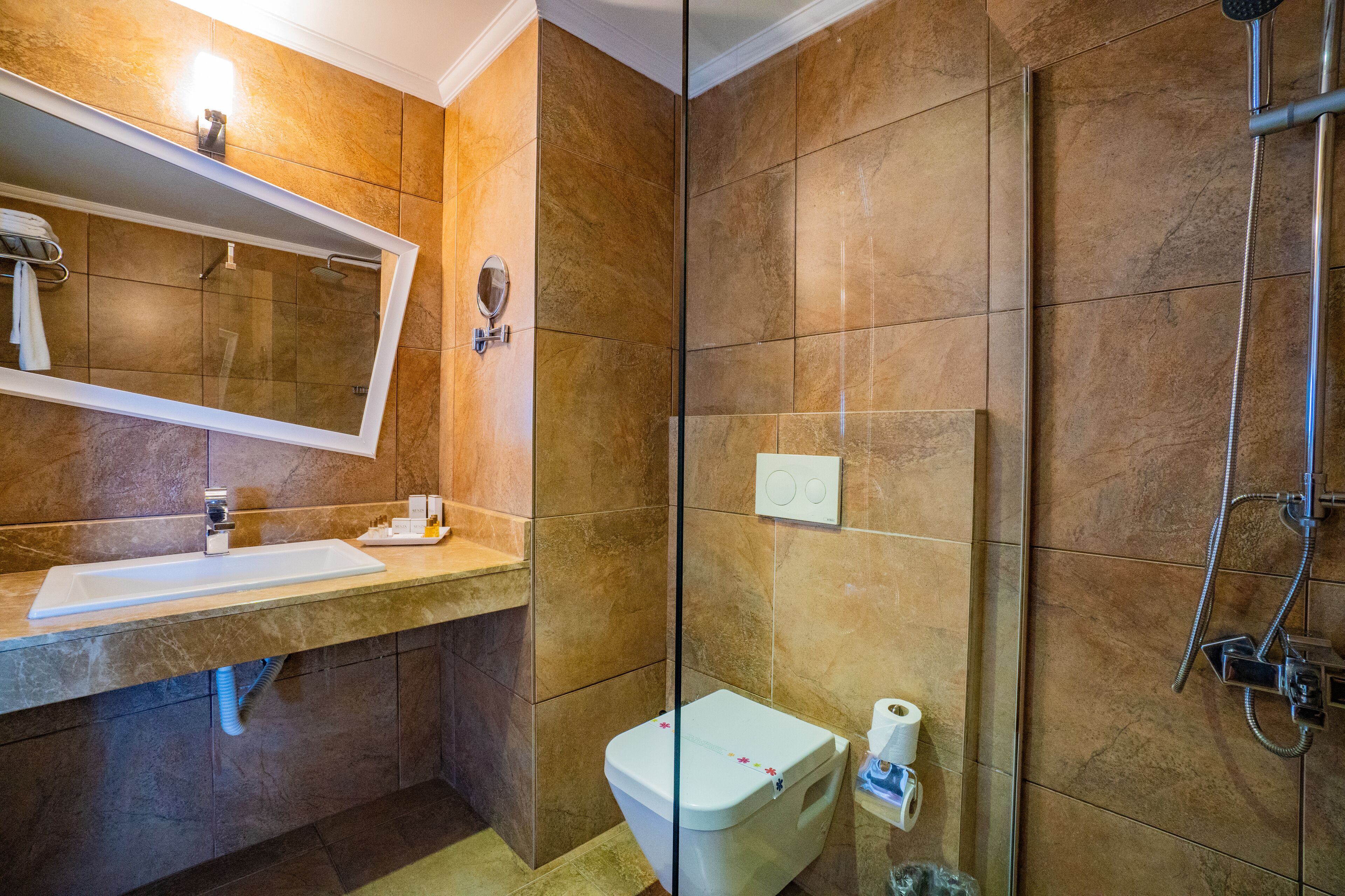 Un baño con lavamanos, espejo, inodoro y ducha.