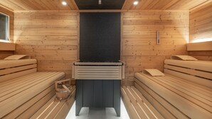 A sauna with wooden benches and a central heating unit. - Hotel Meerzeit Binz (Binz)