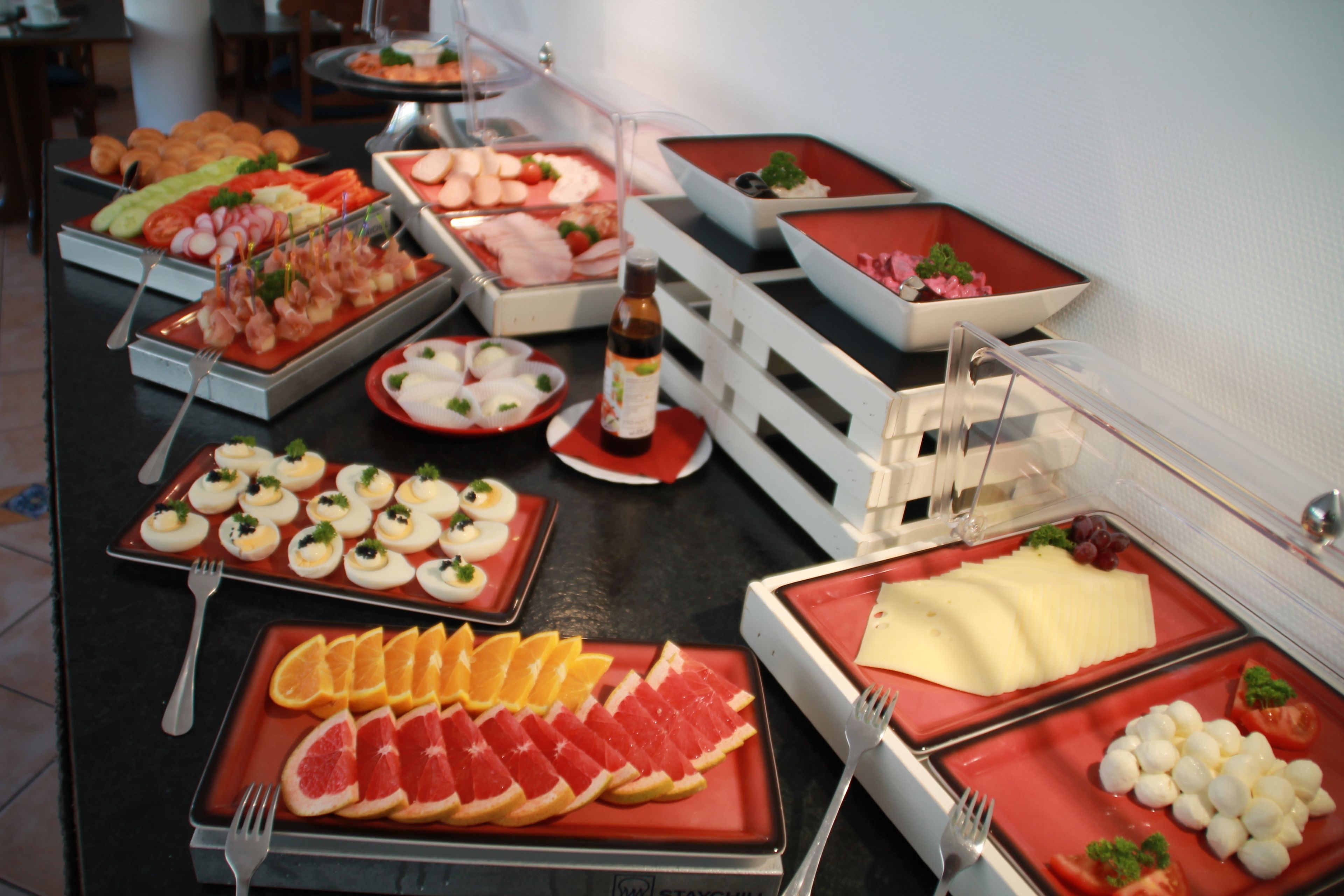 Une table de buffet proposant une variété d’aliments, notamment des fruits, des fromages et des viandes.