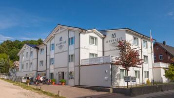 A hotel with a white facade, multiple windows, and a sign indicating it is a hotel.