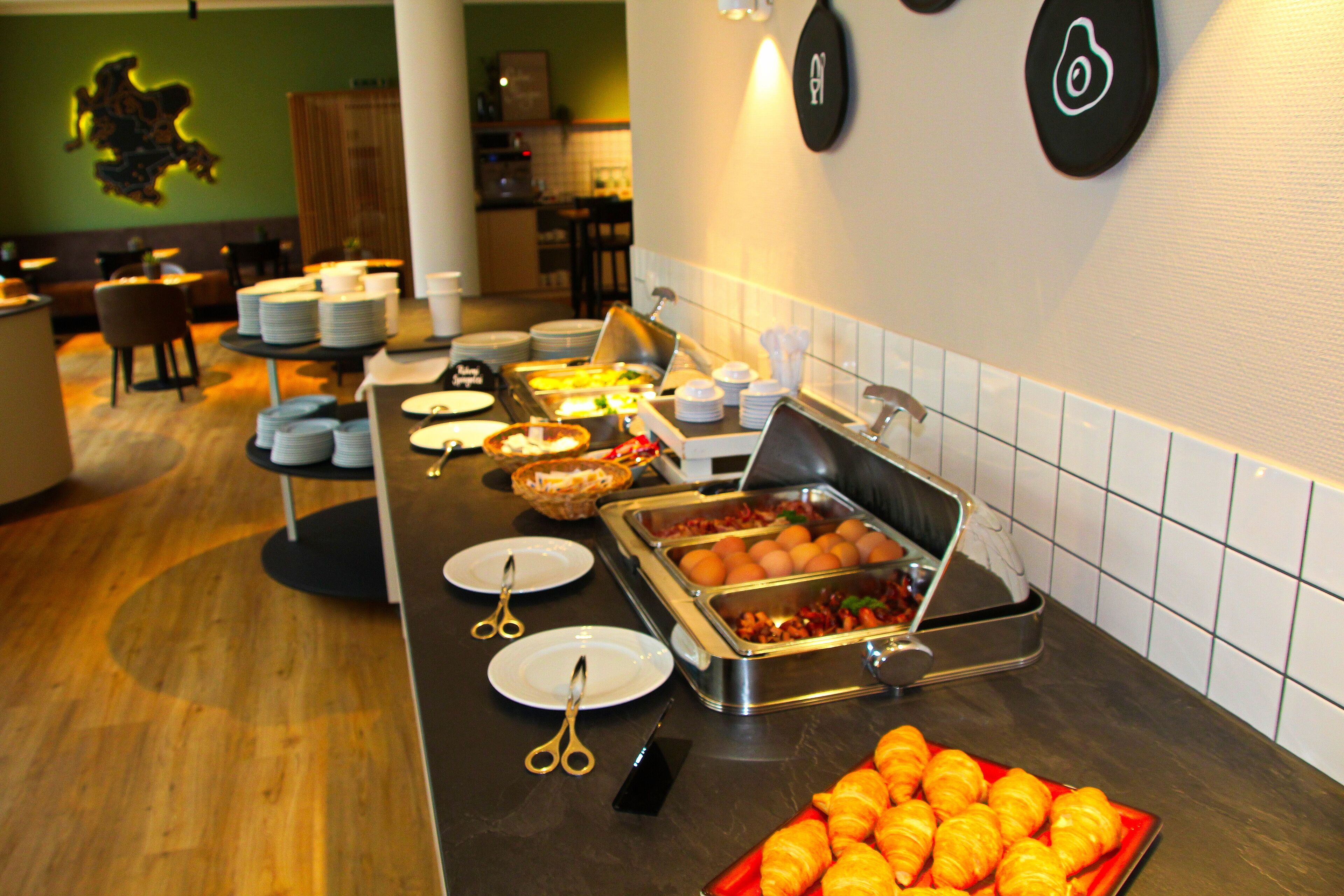 Una mesa de buffet con diversos alimentos, platos y utensilios.