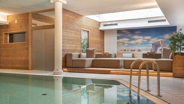 A modern indoor pool area with a glass ceiling, wooden panel walls, and a cityscape mural. - Hotel Meerzeit Binz (Binz)