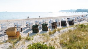 A beach with rows of numbered beach huts and a pier in the background. - Hotel Meerzeit Binz (Binz)