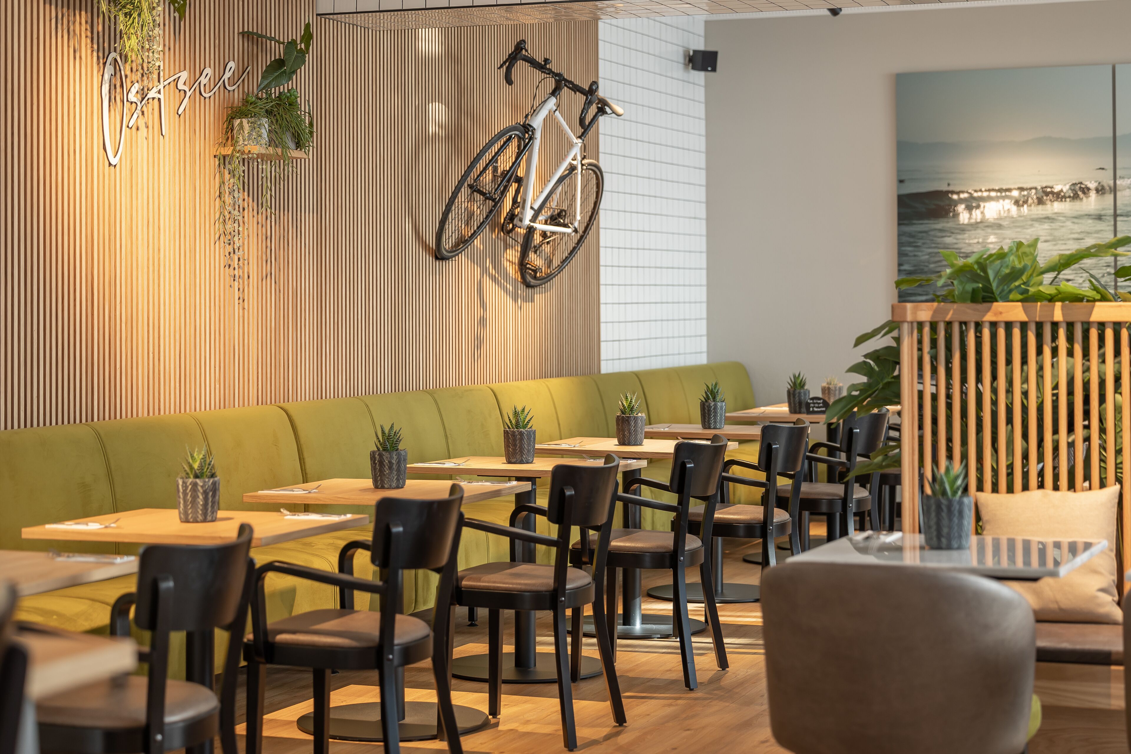 Un intérieur de restaurant moderne avec des lambris en bois, des sièges verts et un vélo accroché au mur.