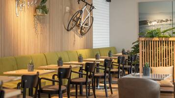 A modern restaurant interior with wooden paneling, green seating, and a bicycle mounted on the wall.