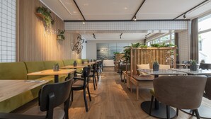 A modern restaurant with wooden flooring, green seating, and a view of the sea. - Hotel Meerzeit Binz (Binz)