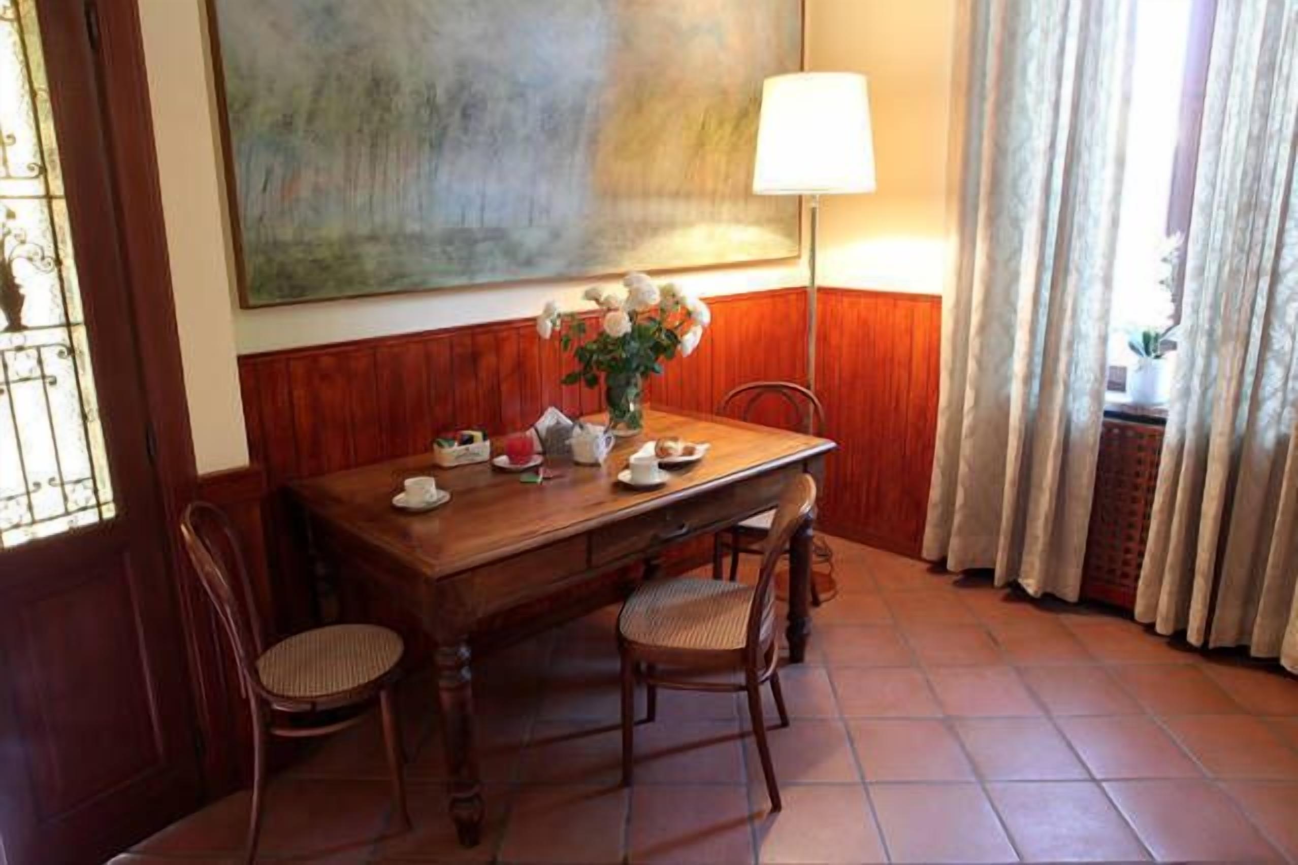 Ein Holztisch mit Stühlen, einer Blumenvase und einer Lampe.