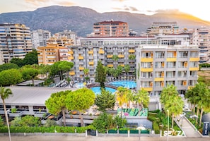 A multi-story hotel with balconies, a swimming pool, and a view of mountains. - Senza Grand Santana Hotel (Alanya)