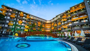 Un hotel con piscina central, varios balcones y un paseo techado.