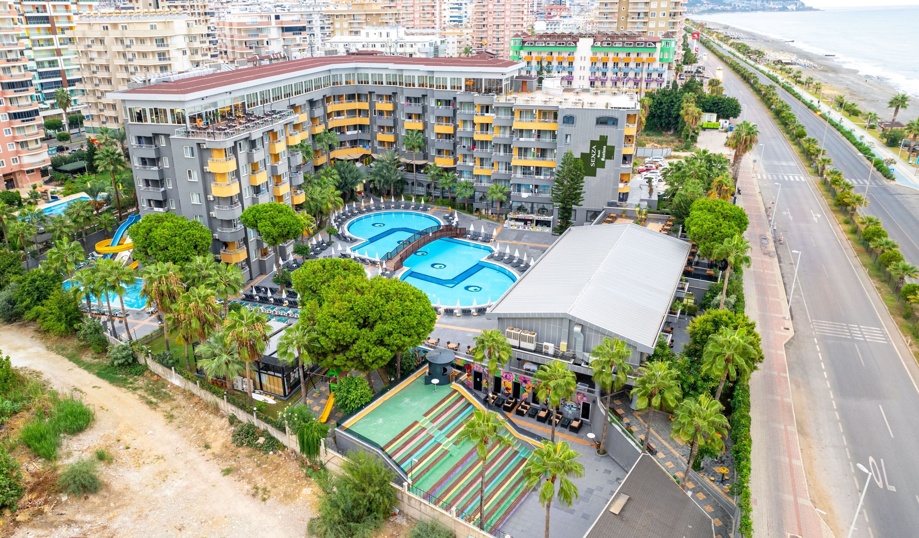 Un hotel de gran altura con varios balcones, piscina y bar en la azotea.