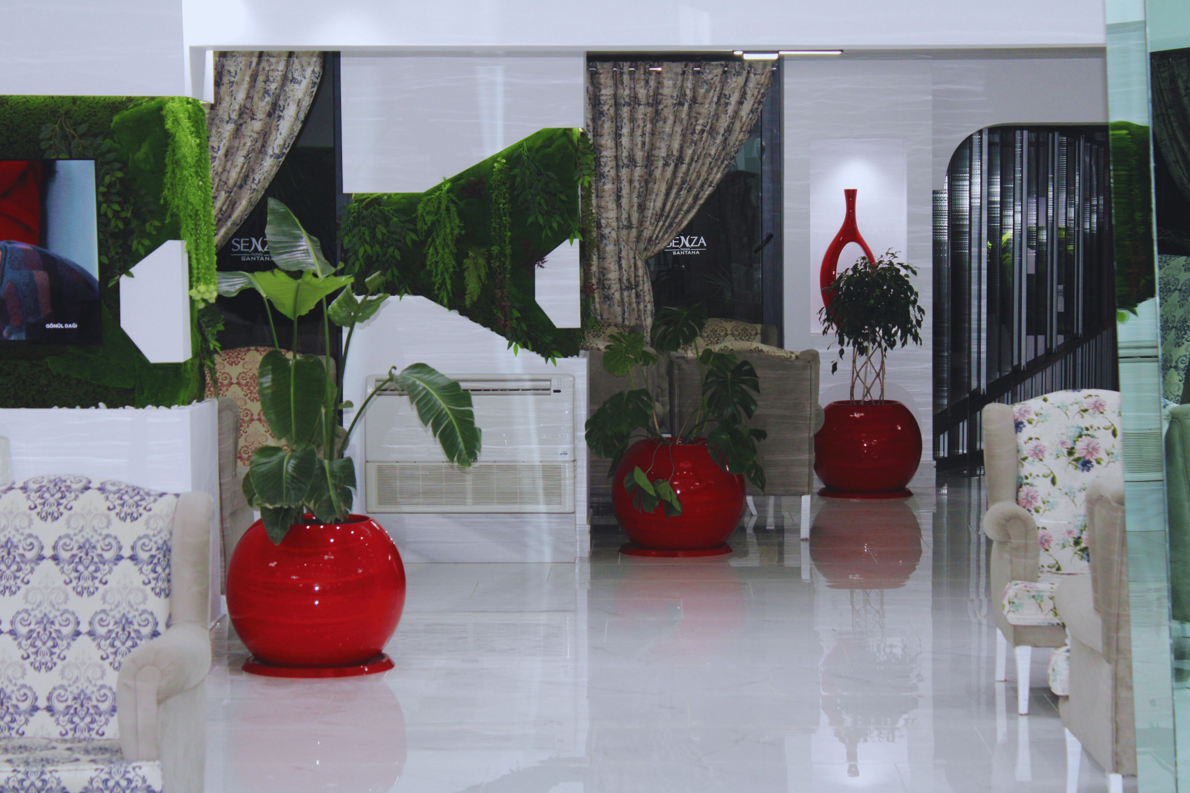 A modern interior with a sofa, a red vase, and a potted plant.
