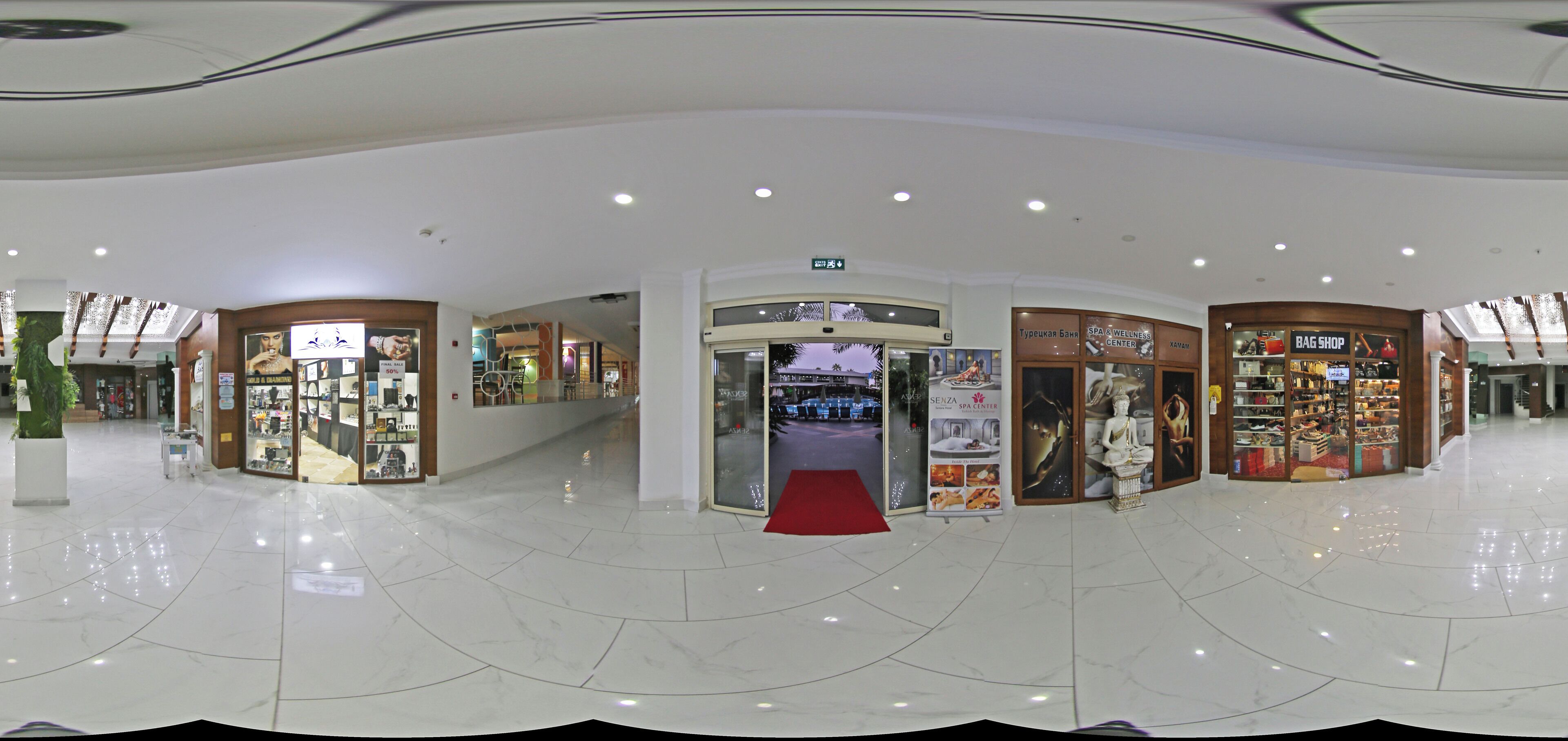 A spacious mall with a clean, polished floor and various stores including a spa center and a bag shop.