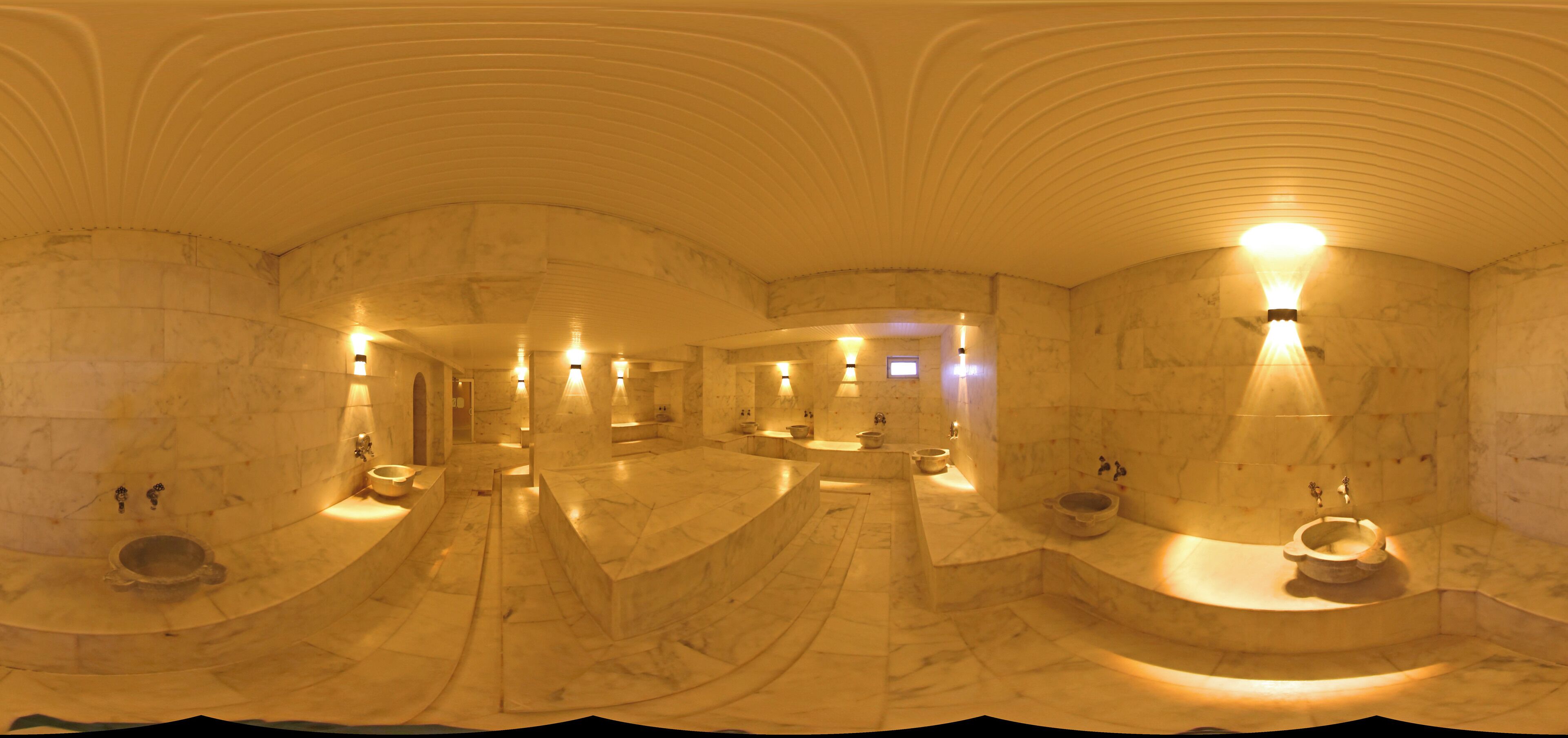 Un spa lujoso con suelos de mármol, varios lavamanos e iluminación tenue.