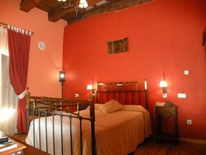 A room with a bed, two wall-mounted lamps, a small table, and a red curtain. - La Posada de Carmen (Chane)