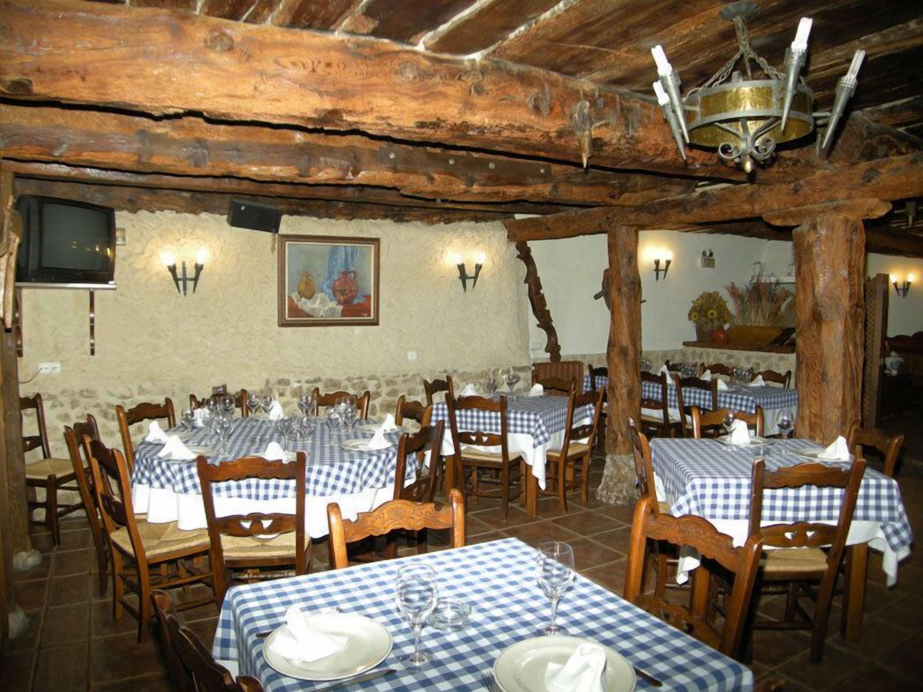 Un restaurante rústico con vigas de madera, manteles a cuadros y decoración tradicional.