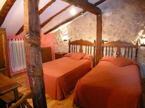 A rustic room with two wooden beds, stone walls, and exposed wooden beams. - La Posada de Carmen (Chane)