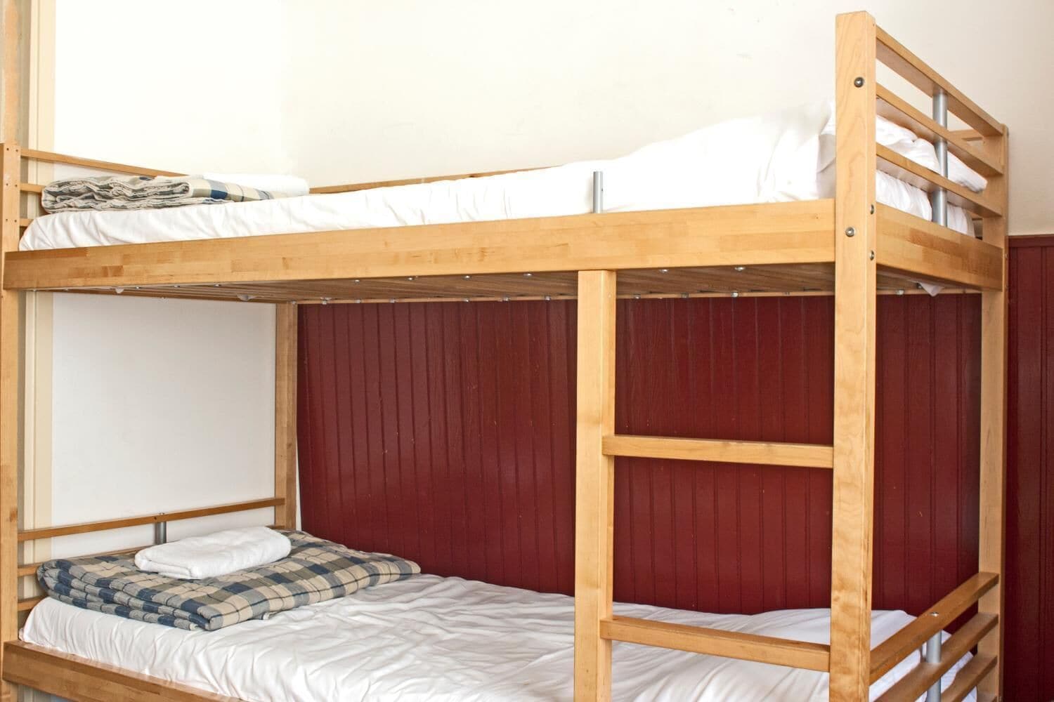 A bunk bed with a wooden frame and a red headboard.