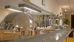 Montaje de bufé con estaciones de comida cubiertas y cestas de pan.