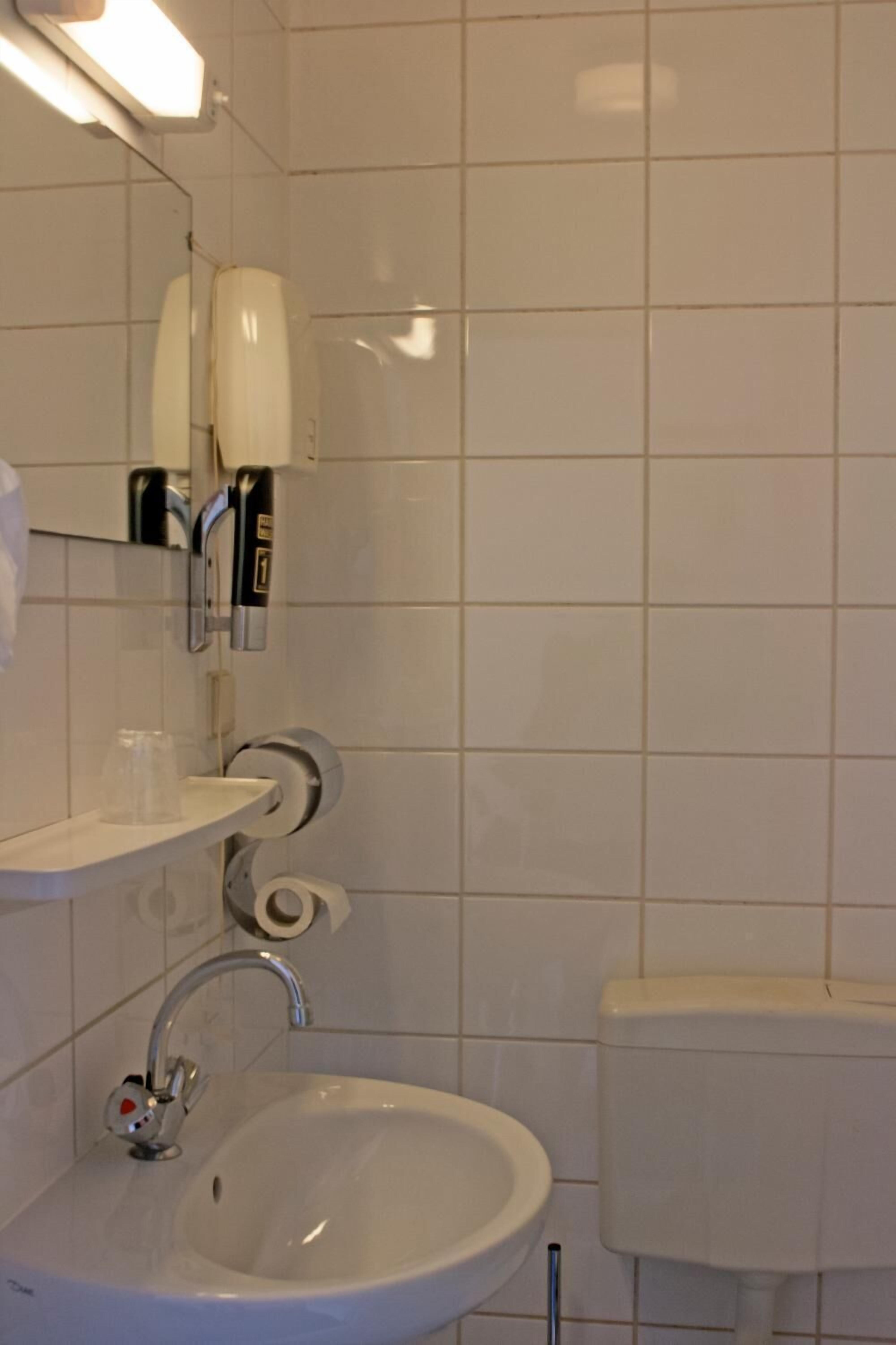 Un baño con lavamanos blanco, un espejo y un inodoro.