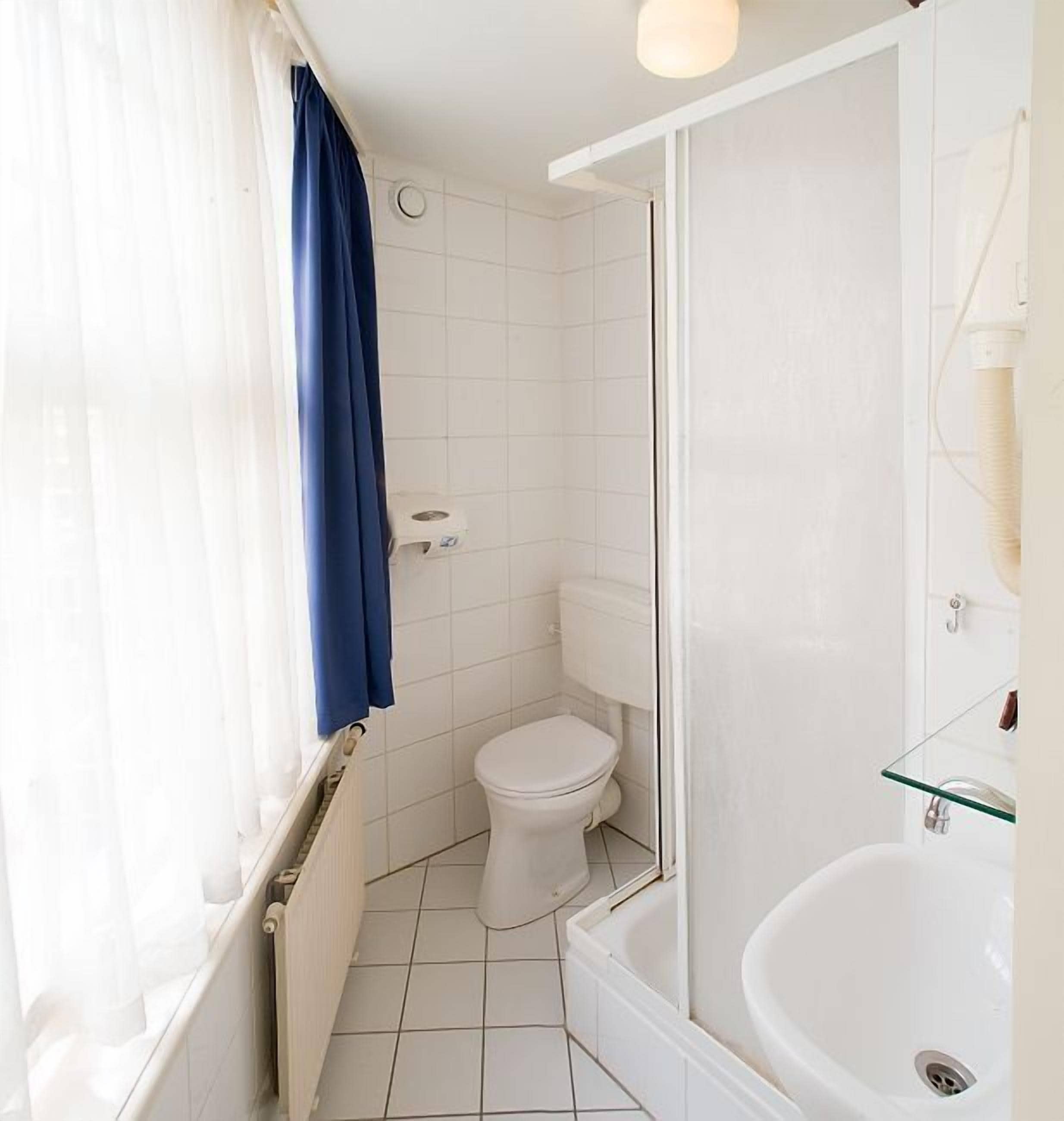 A small, clean bathroom with a toilet, a glass shower enclosure, and a bathtub.