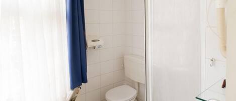 A small, clean bathroom with a toilet, a glass shower enclosure, and a bathtub.