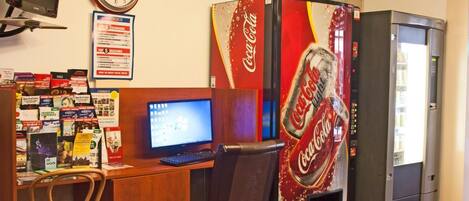 Een kamer met een bureau, een computer en een Coca-Cola automaat.