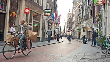 A street with shops and restaurants, including a grill restaurant and a pizza place.