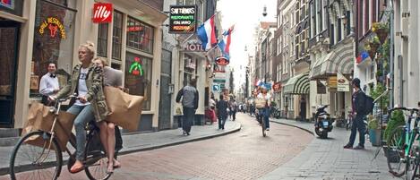 A street with shops and restaurants, including a grill restaurant and a pizza place.