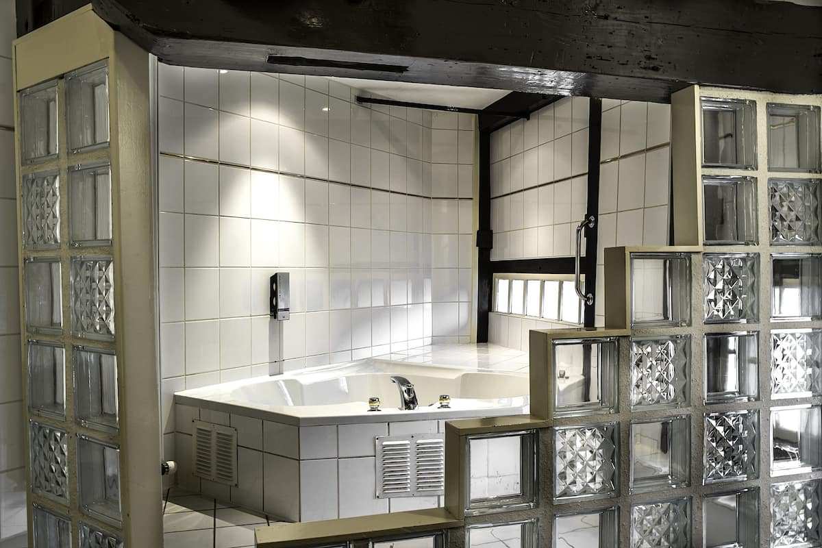 A modern bathroom with a large bathtub, tiled walls, and decorative glass panels.