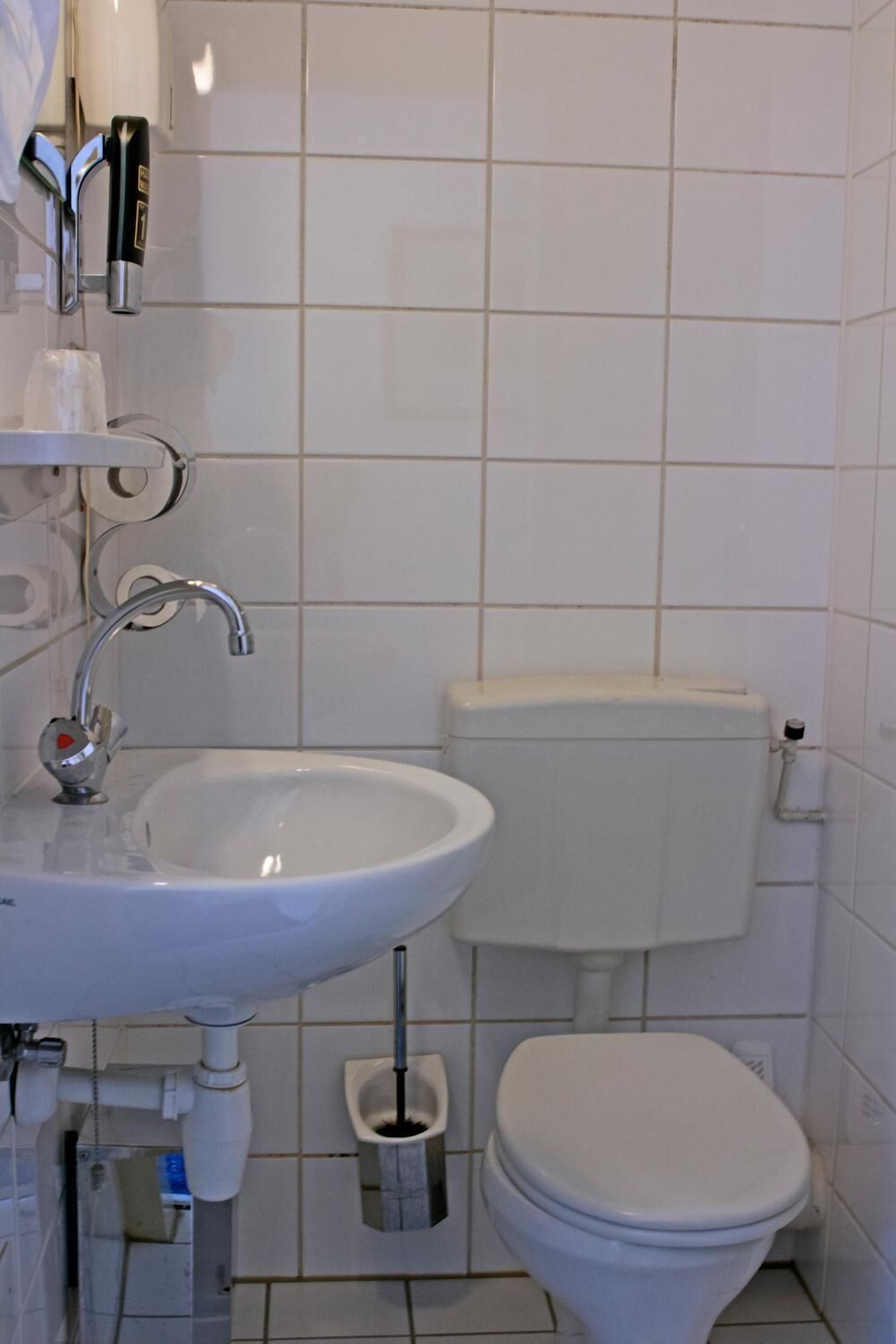A bathroom with a white sink, a toilet, and a bidet.