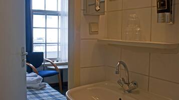 A bathroom with a sink, a mirror, a towel rack, and a window.