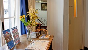A hotel reception area with a desk, a vase with flowers, a map, and a signboard. - Hotel De Koopermoolen (Amsterdam)