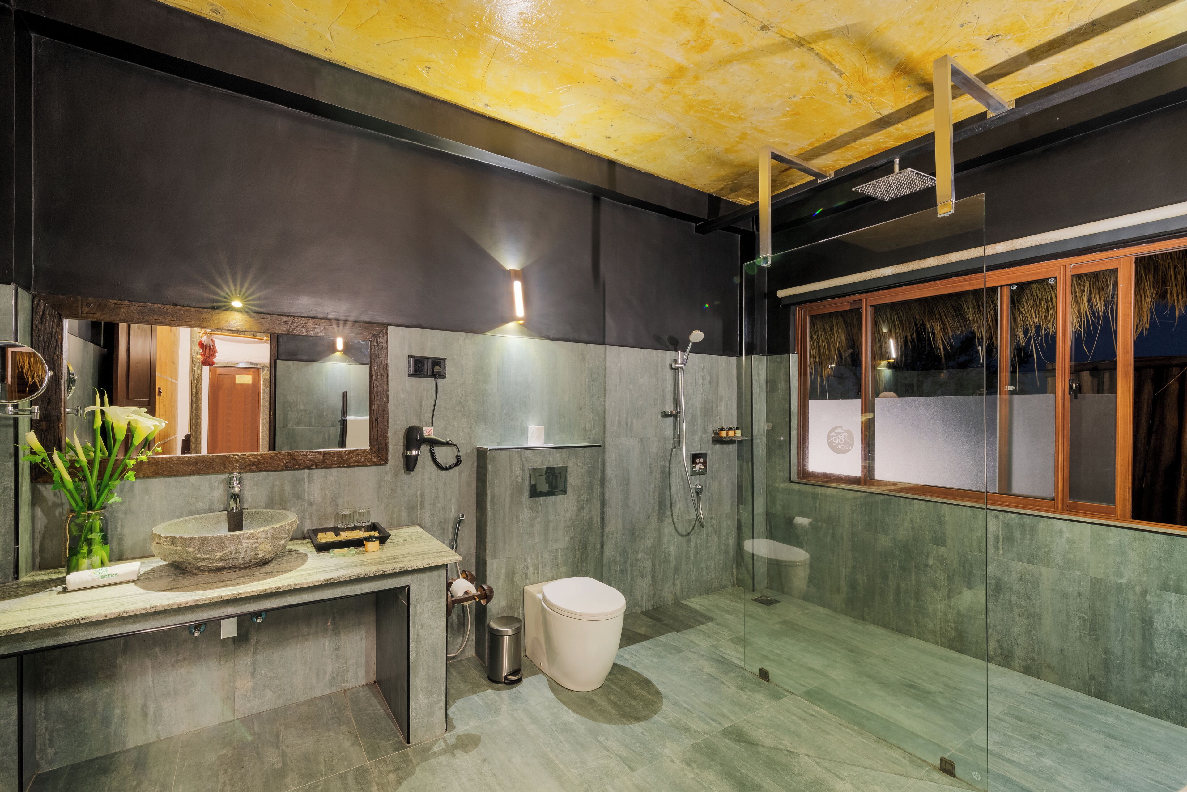 Une salle de bain moderne avec un grand miroir, un lavabo en pierre, des toilettes et un espace douche.
