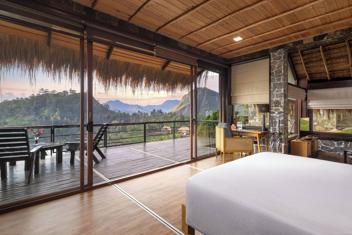 A spacious balcony with a wooden floor, a bed, and a desk with a computer.