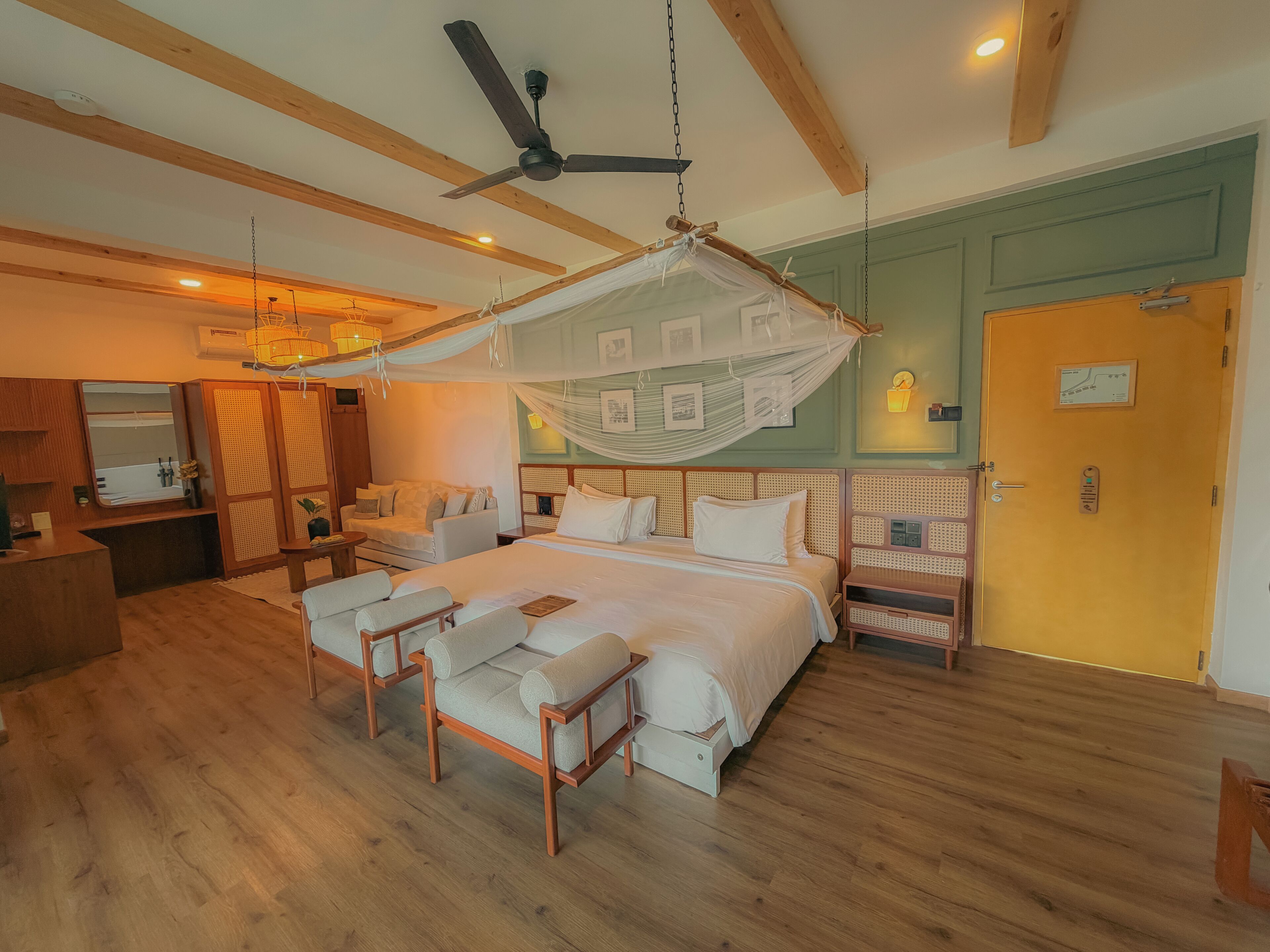 Un dormitorio con cama, mesitas de noche, una silla, ventilador de techo y dosel sobre la cama.