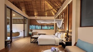 A spacious bedroom with a large bed, bedside tables, a hanging chair, and a view of trees through the window. - 98 Acres Resort & Spa (Ella)