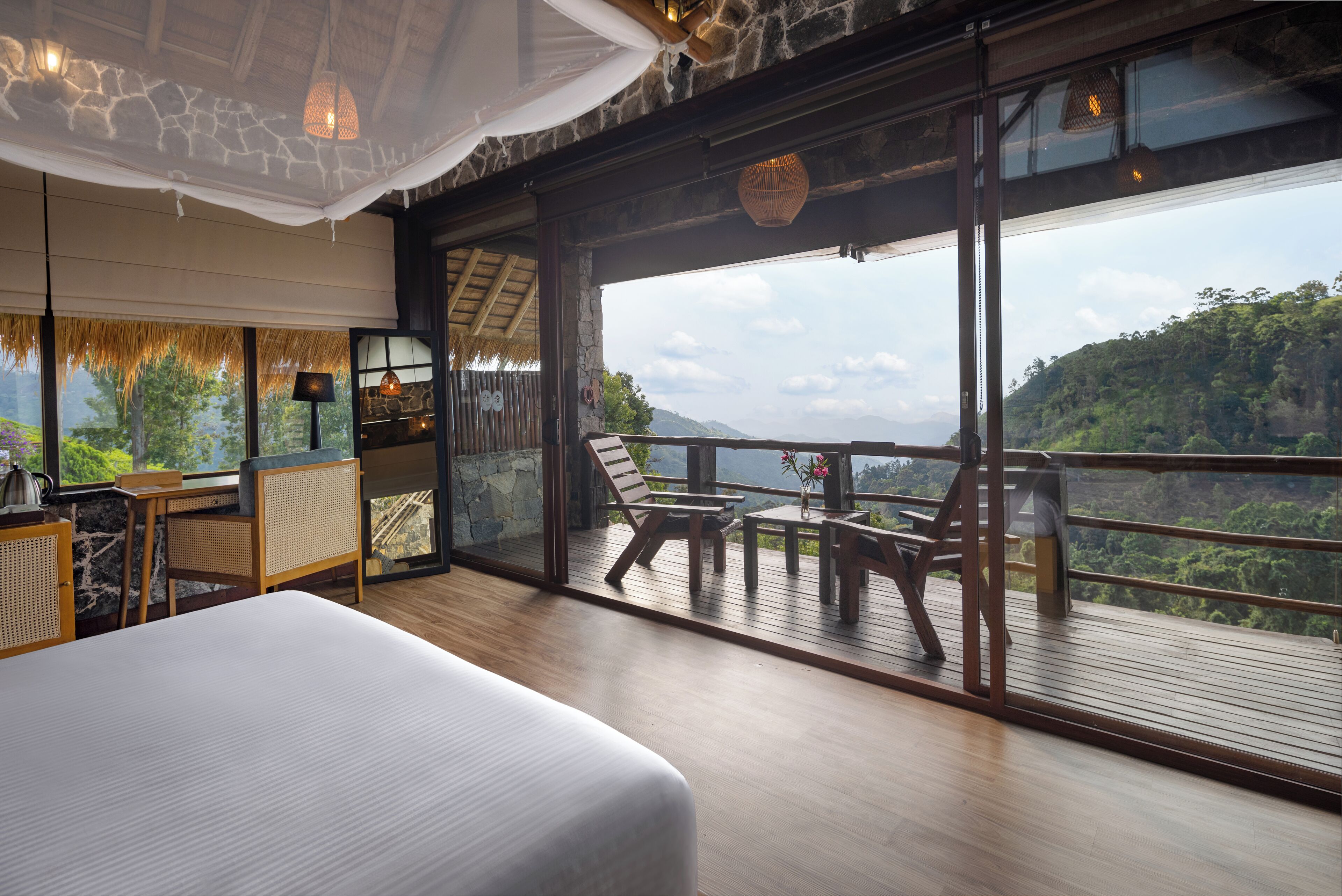 A spacious balcony with a wooden deck, a bed, and a dining area with a table and chairs.
