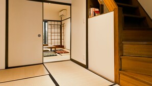 A traditional Japanese room with tatami flooring, a sliding door, and a wooden staircase. - Hashibaan (Kanazawa)