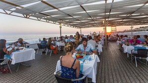 Ein Essbereich im Freien mit Tischen und Stühlen mit Blick auf das Meer.