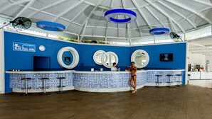 Eine blau-weiße Bar mit hoher Decke und runden Deckenleuchten.