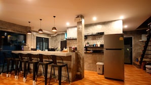 A modern kitchen with a bar area, wooden flooring, and a stainless steel refrigerator. - Aonang Lodge (Krabi)