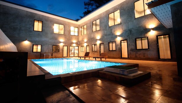 A modern building with a swimming pool, multiple windows, and outdoor seating. - Aonang Lodge (Krabi)
